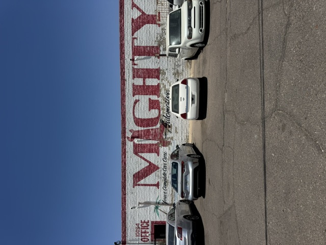 The Mighty Automotive building with its hand-painted brick wall reading Your Complete Car Care